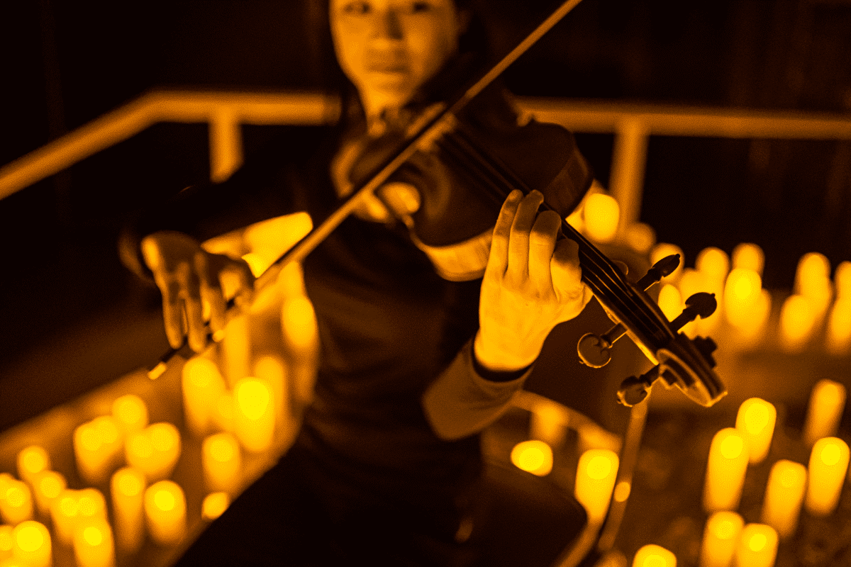 A musician playing a violin by candlelight