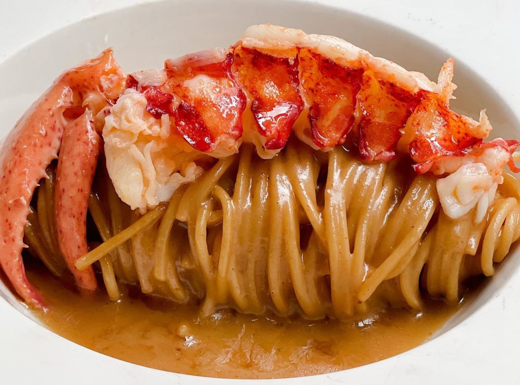 A lobster tail and claw sitting atop some pasta.