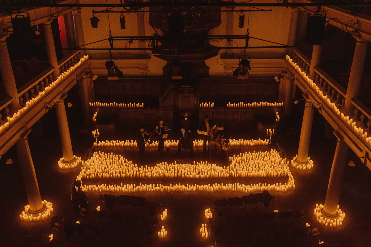 A string quartet performs on a stage covered in candles at Rode Hoed in Amsterdam.