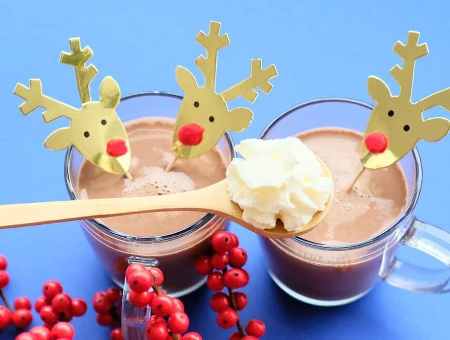Two glasses of hot chocolate, decorated with paper reindeer. 