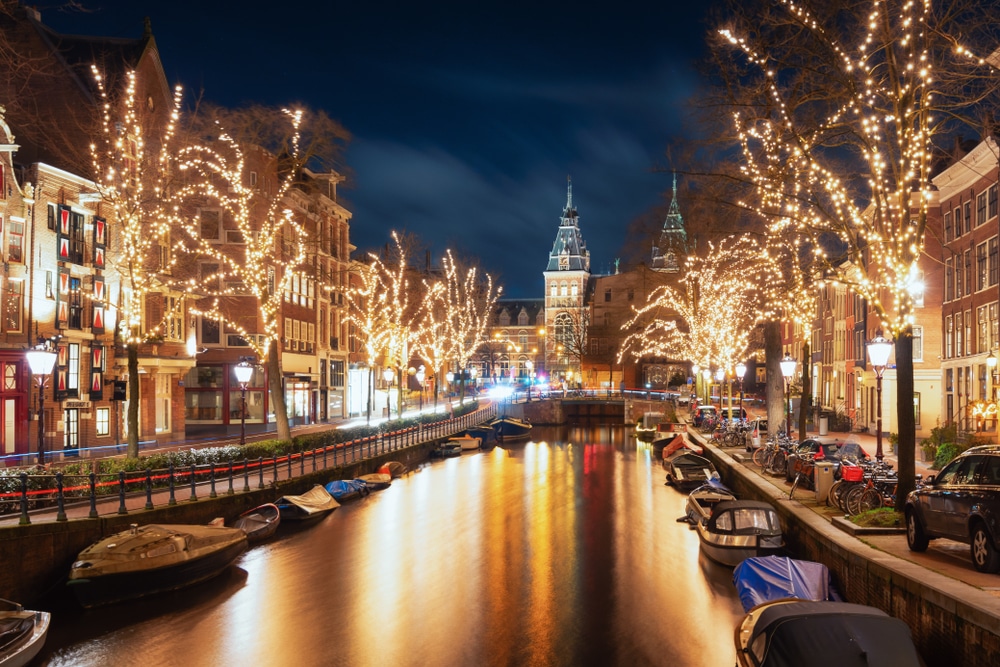 Lights strung with fairylights sparkle either side of a canal in Amsterdam.