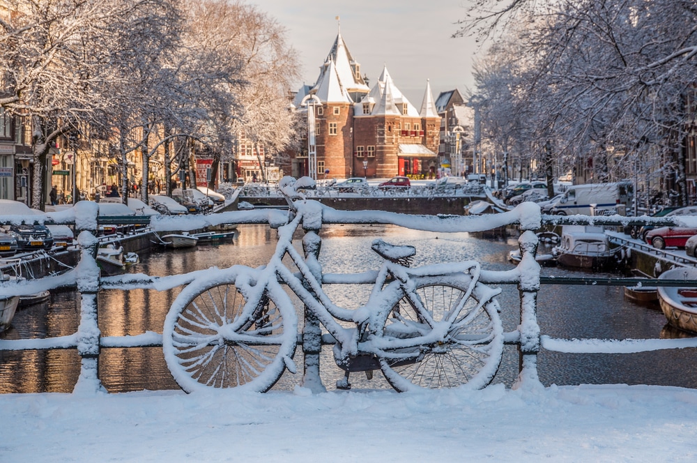 Snow coats a bike by a canal in Amsterdam.