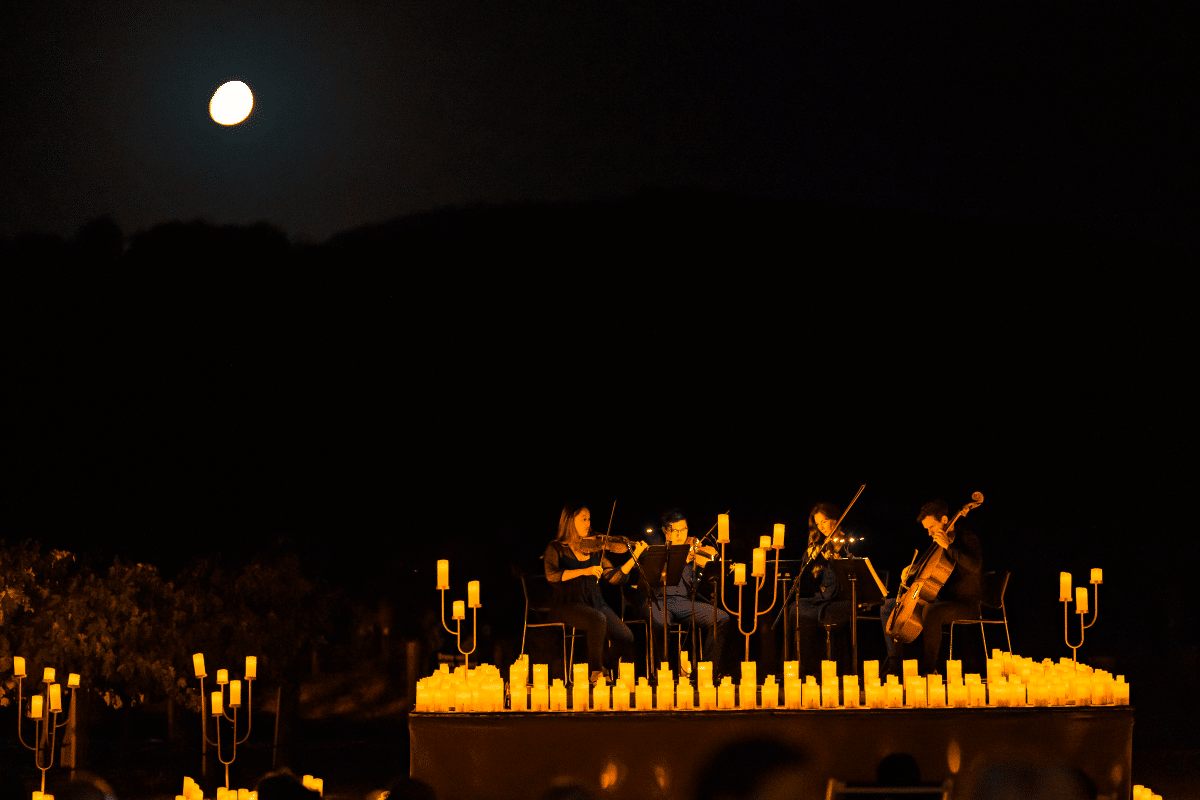 A string quartet performing on stage in the glow of candlelight